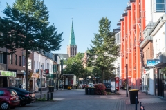 Blick auf eine Straße in Heinsberg mit einem Kirchturm im Hintergrund und modernen Gebäuden.